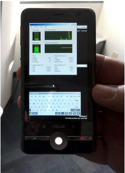 A hand holding a mobile device with Task Manager and onscreen keyboard